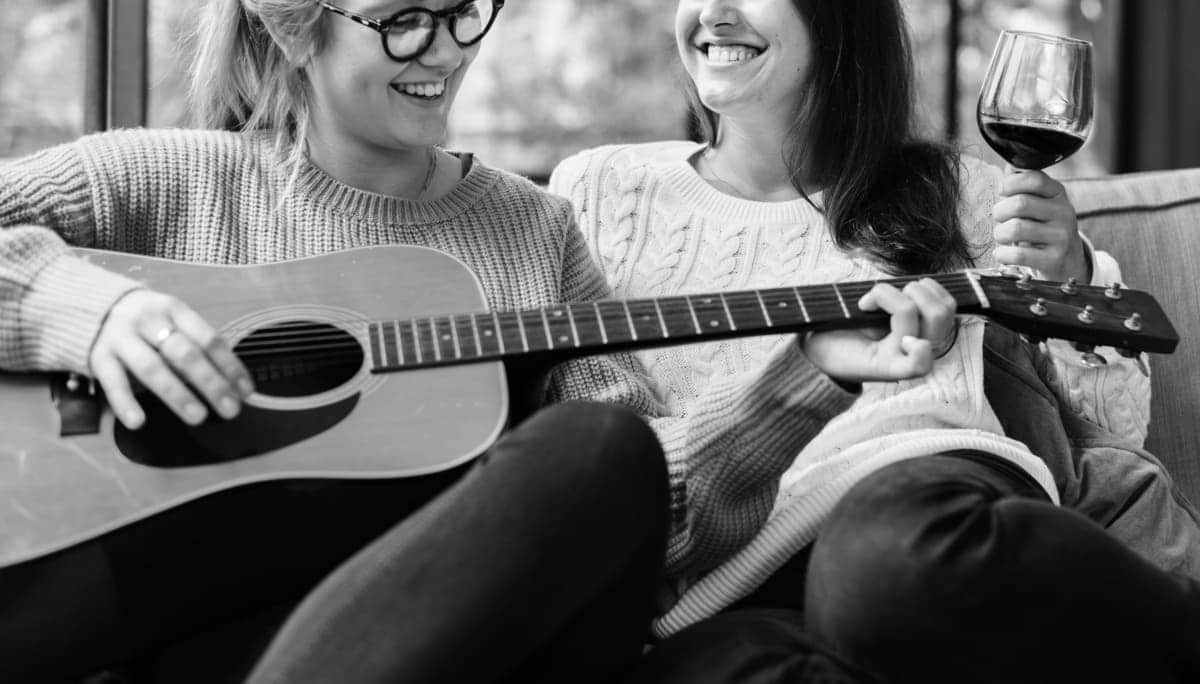 woman drinking wine and playing guitar