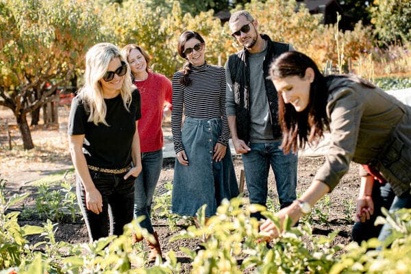woman pointing out plants in garden to group of people