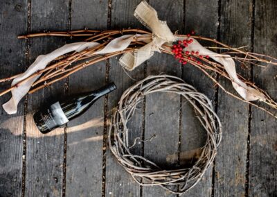 hill family estate bottle of wine on table next to wreath made of grape vines